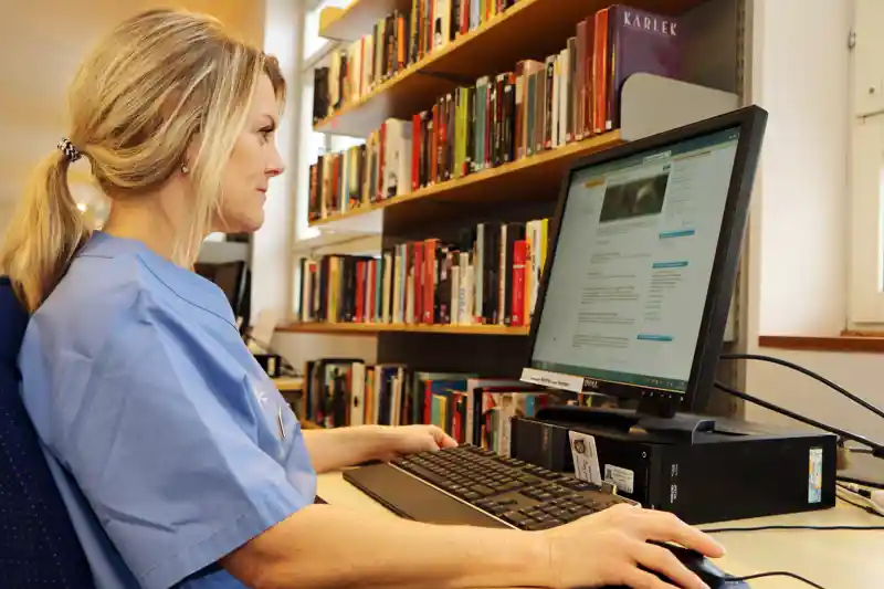 Sjuksköterska använder dator på biblioteket.