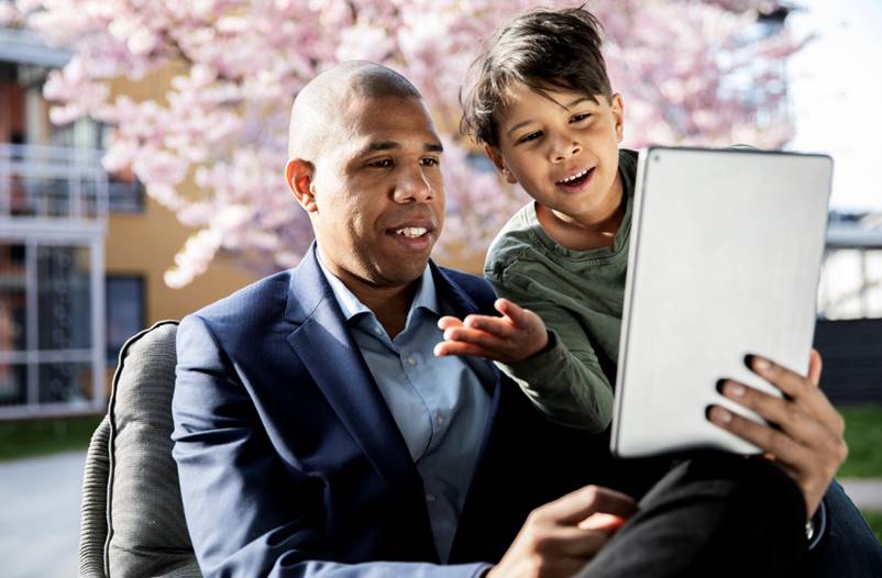 En man som håller i en laptop  tillsammans med ett barn 