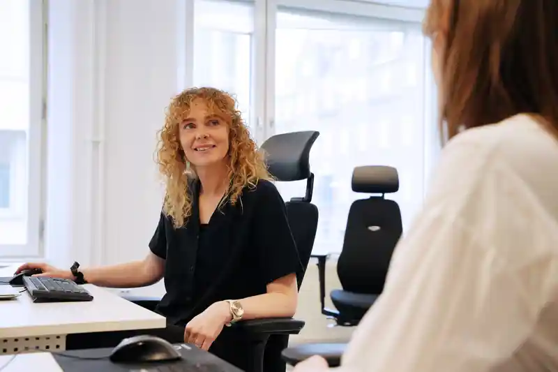 En kvinna sitter vid ett skrivbord framför en dator.