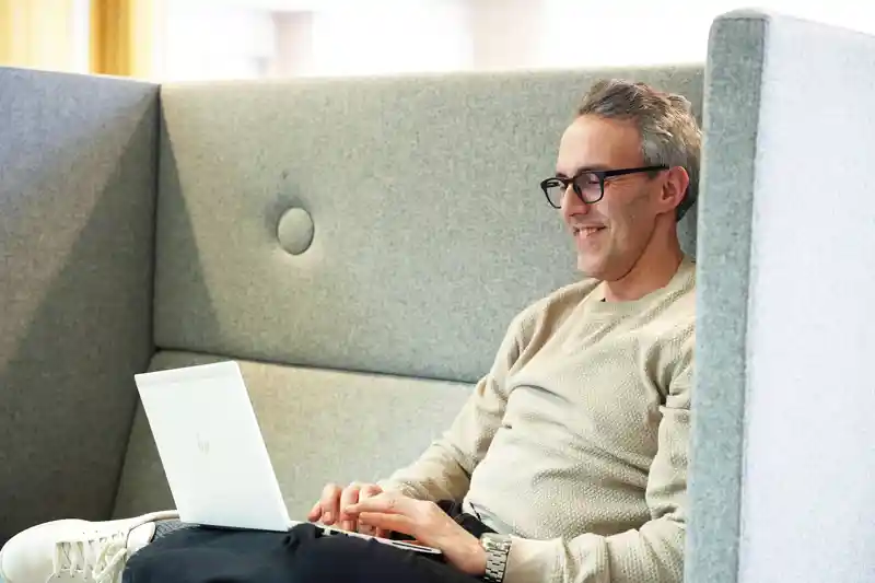 En man sitter i en soffa och använder en bärbar dator.