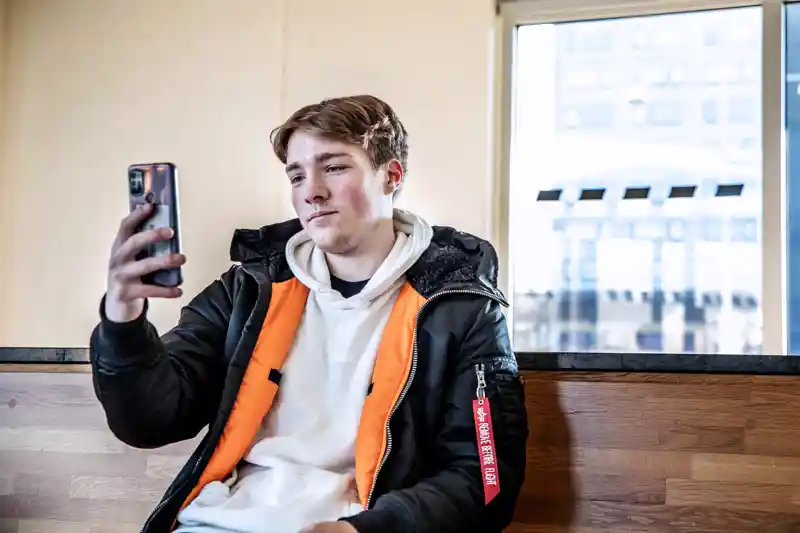 Ung kille som sitter och pratar i telefon med videosamtal.