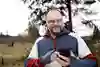 Man som står utomhus och använder sin mobiltelefon.