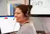 Glad kvinna med headset vid datorskärm.