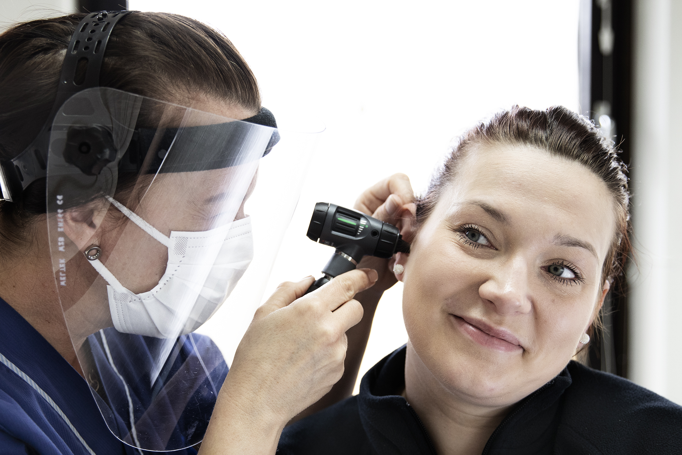 Vårdpersonal tittar i en patients öra.