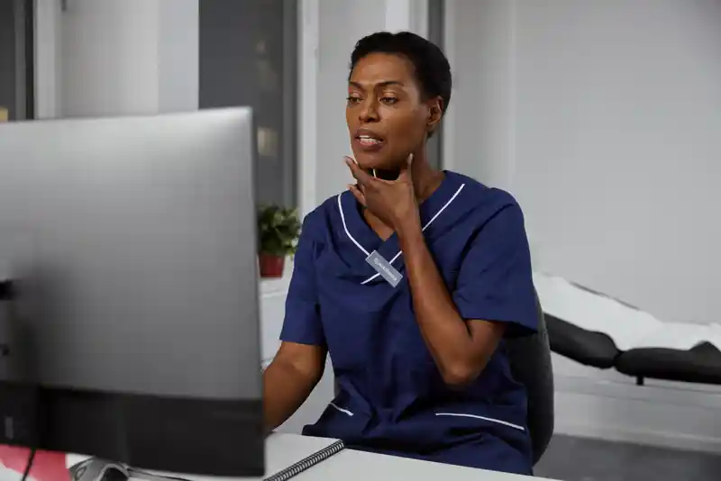 Sköterska som sitter vid dator och har videosamtal.