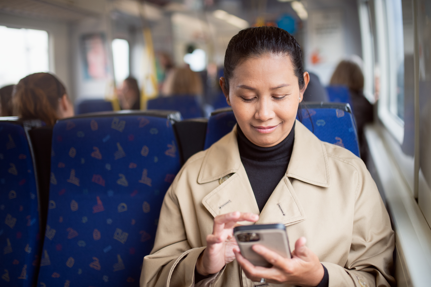 Bild på kvinna på tåg som kollar på sin telefon
