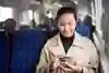 Bild på kvinna på tåg som kollar på sin telefon