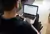 Person i rullstol med en bärbar dator i knät.
