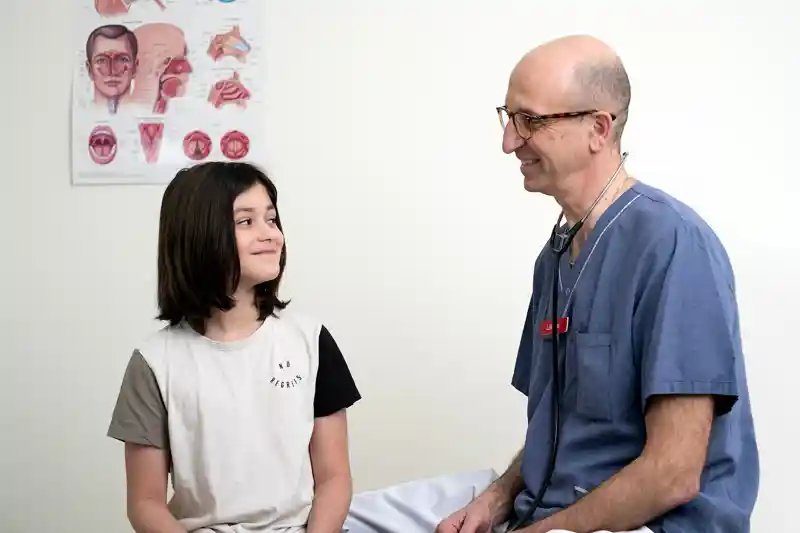 Ungdom och läkare tittar på varandra i undersökningsrum.