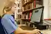 Sjuksköterska använder dator på biblioteket.