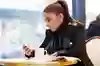 Ung kvinna med mobiltelefon på café