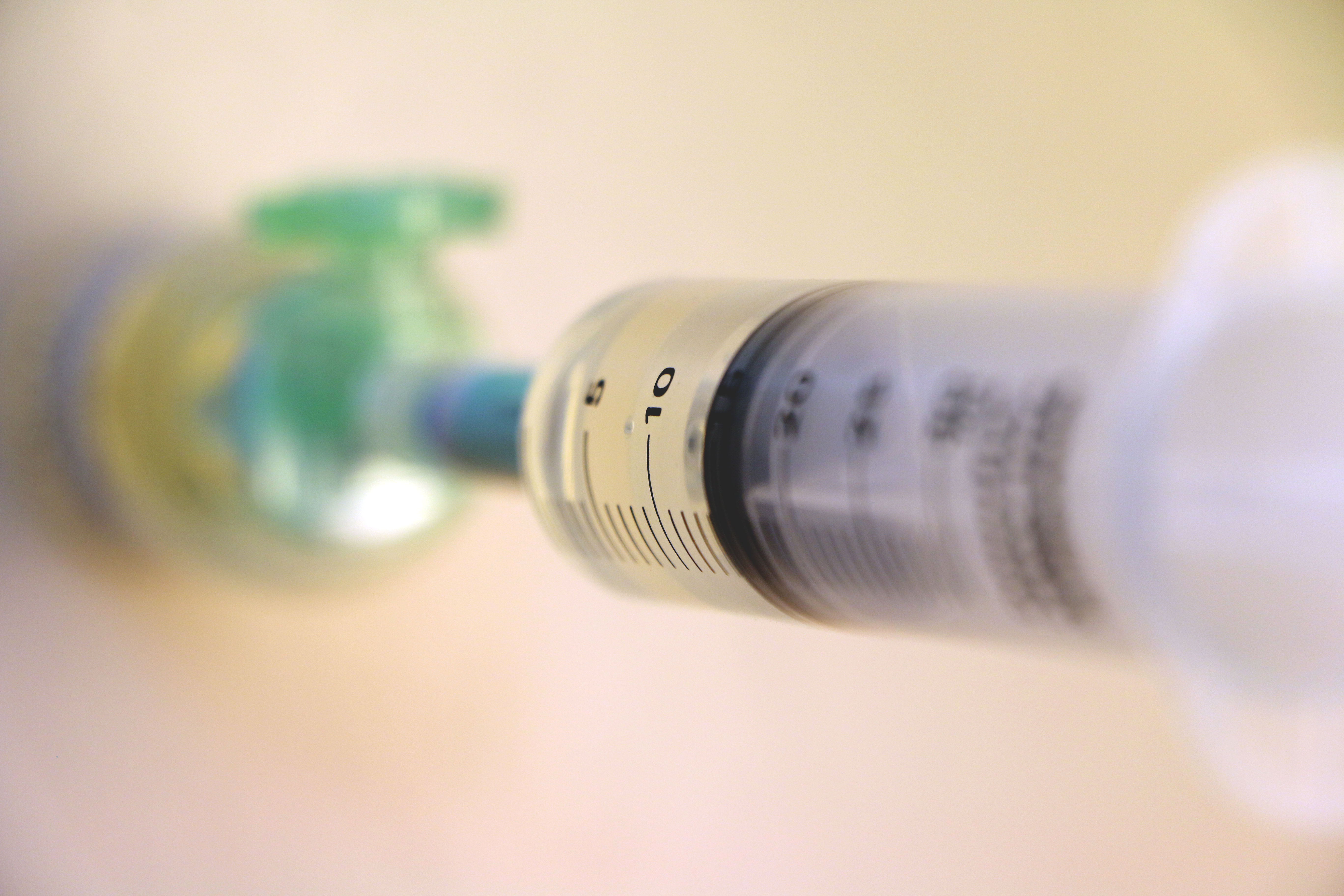 Närbild på kanyl som drar upp vätska från en medicinflaska.