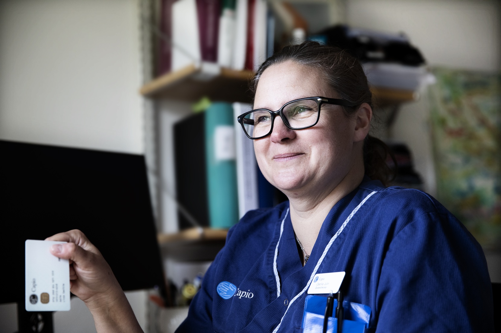 En kvinna i operationskläder håller i ett kort.