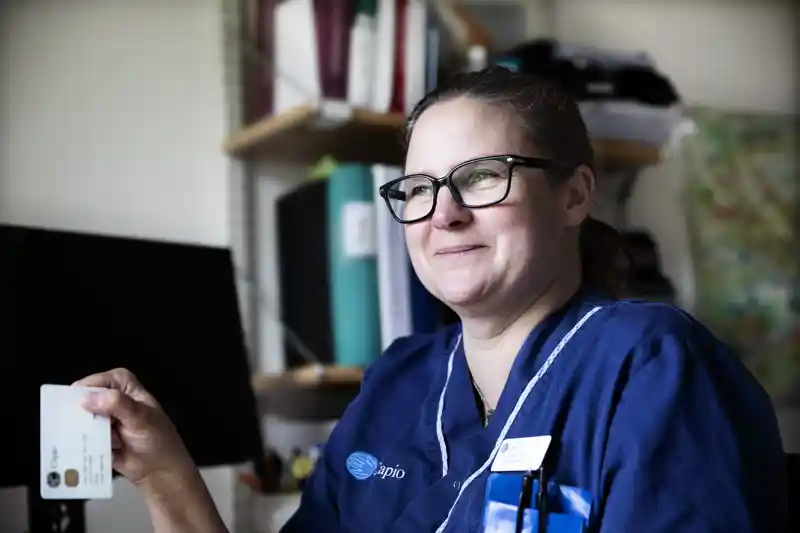 En kvinna i operationskläder håller i ett kort.