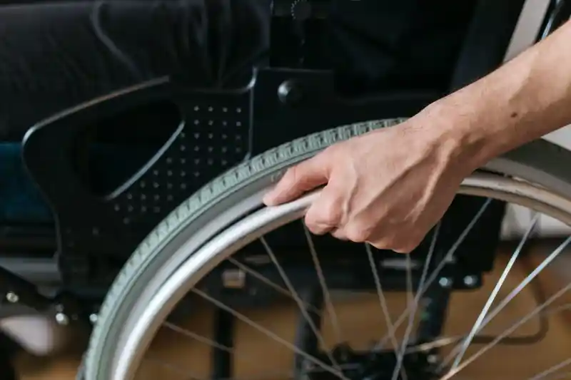 En hand på ett rullstolsdäck.