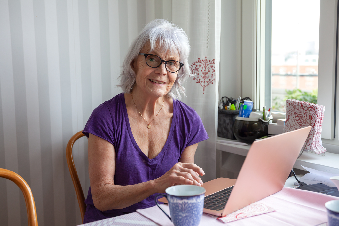 Bild på äldre kvinna som sitter vid dator