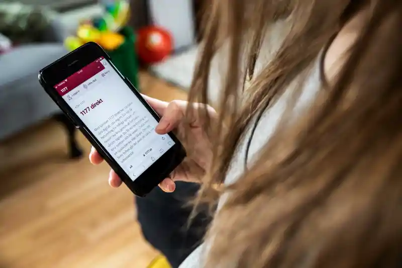 Bild på person som håller i en mobiltelefon och använder 1177 direkt